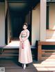 A woman in a pink kimono standing in front of a building.