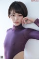 A woman in a purple bodysuit posing for a picture.