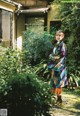 A woman in a colorful kimono standing in a garden.