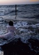 A woman in a white dress sitting in the ocean.