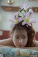 A woman laying on a bed with a flower in her hair.