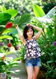 A woman standing in front of a bunch of plants.